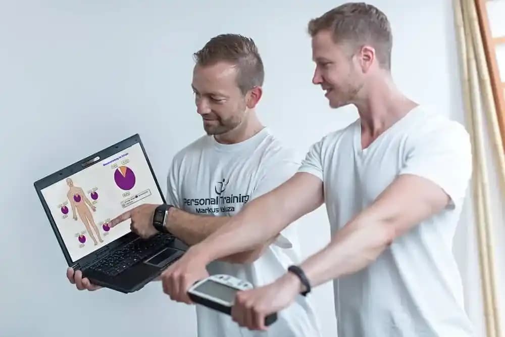 Trainer bei Durchführung einer Körperanalyse mit Klienten